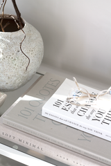 101 Essays That Will Change the Way You Think by Brianna Wiest styled on neutral books with clear glasses and a textured ceramic vase.