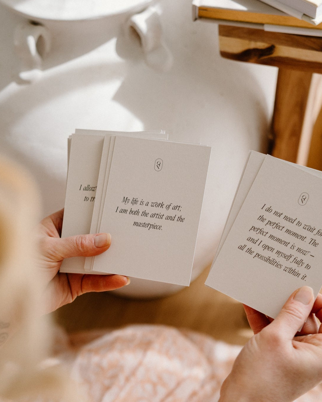 Hands holding an affirmation card beside a white lamp