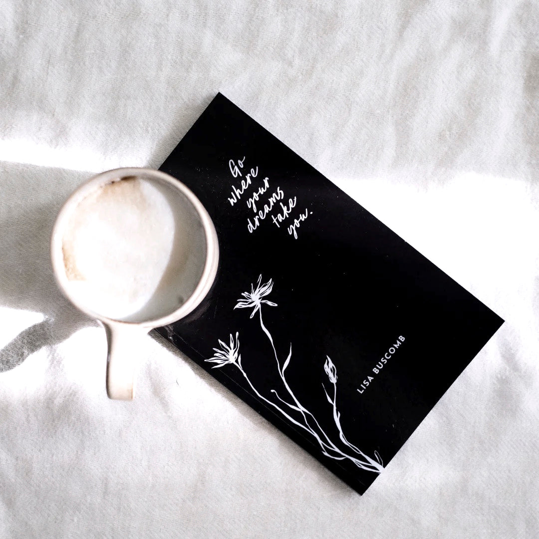 The book lying on white bedding beside a mug