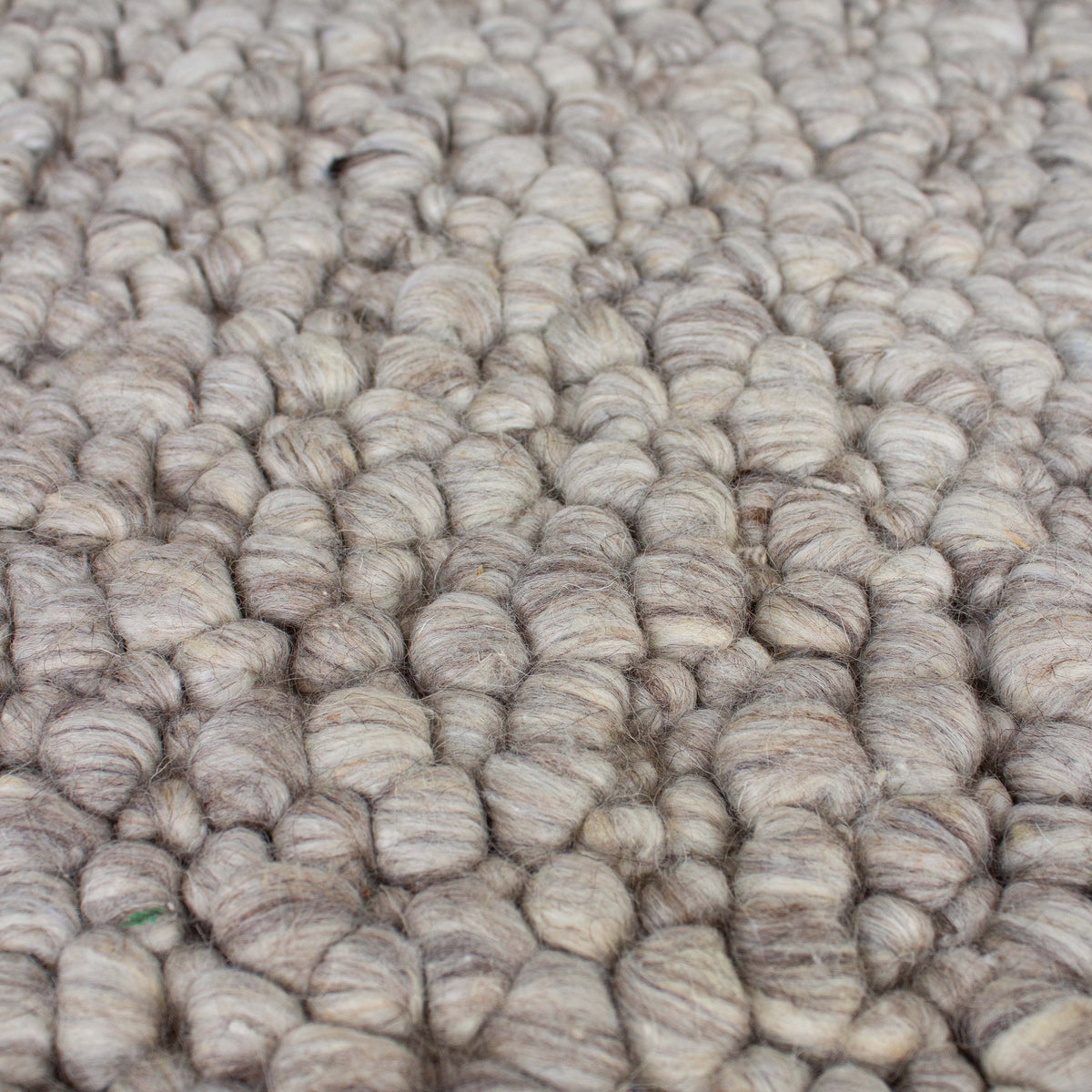 Close view of the pebble-like wool loops in mixed warm grey tones