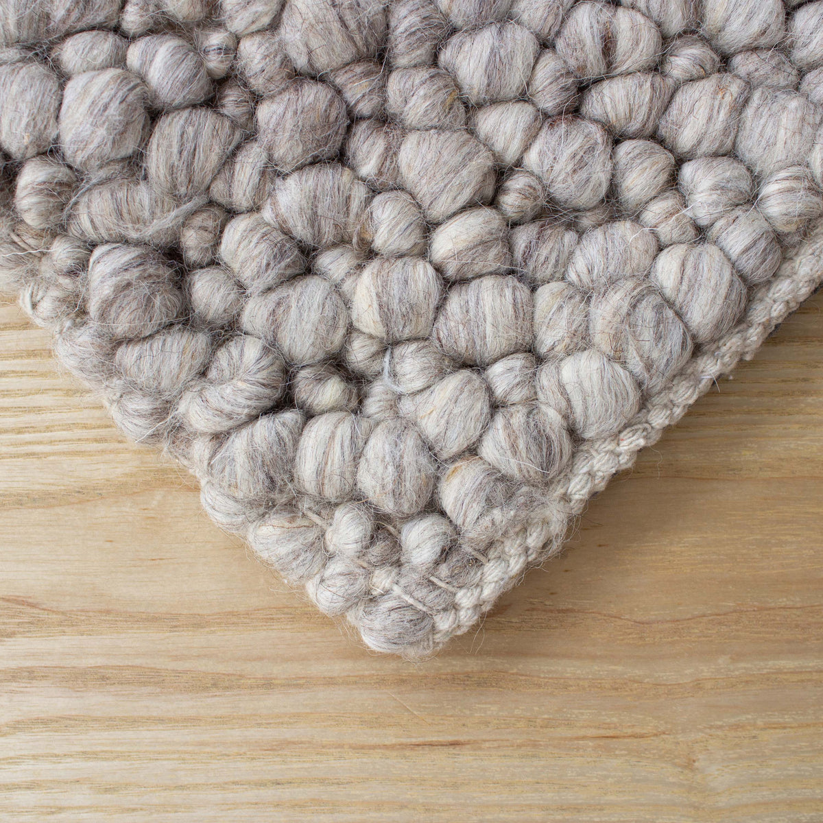 Corner of the warm grey pebble rug on a timber floor