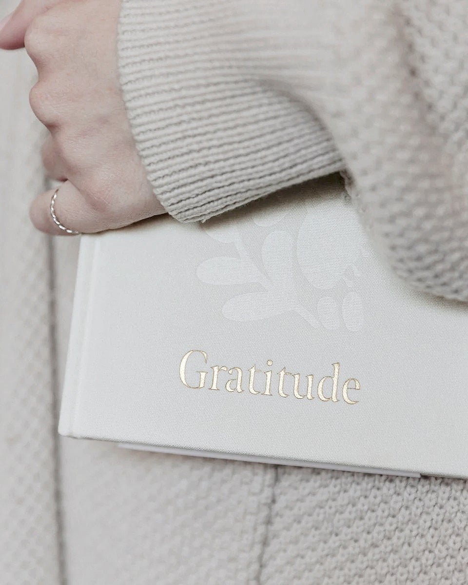 Gratitude journal held against a soft knit jumper