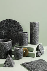 A group of Zakkia Terrazzo Pots - Black with a minimalist design on a green surface.
