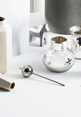 A collection of Zakkia Stem Tea Strainers - Brass / Silver and other objects on a white surface.