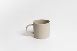 A Jon Boy Mug sitting on a white surface, embodying a natural palette and organic form.