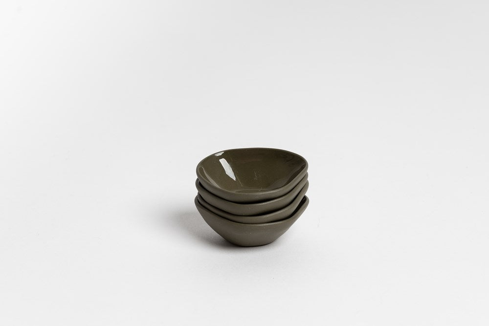 Stack of olive green Haan mini dishes, on pale grey