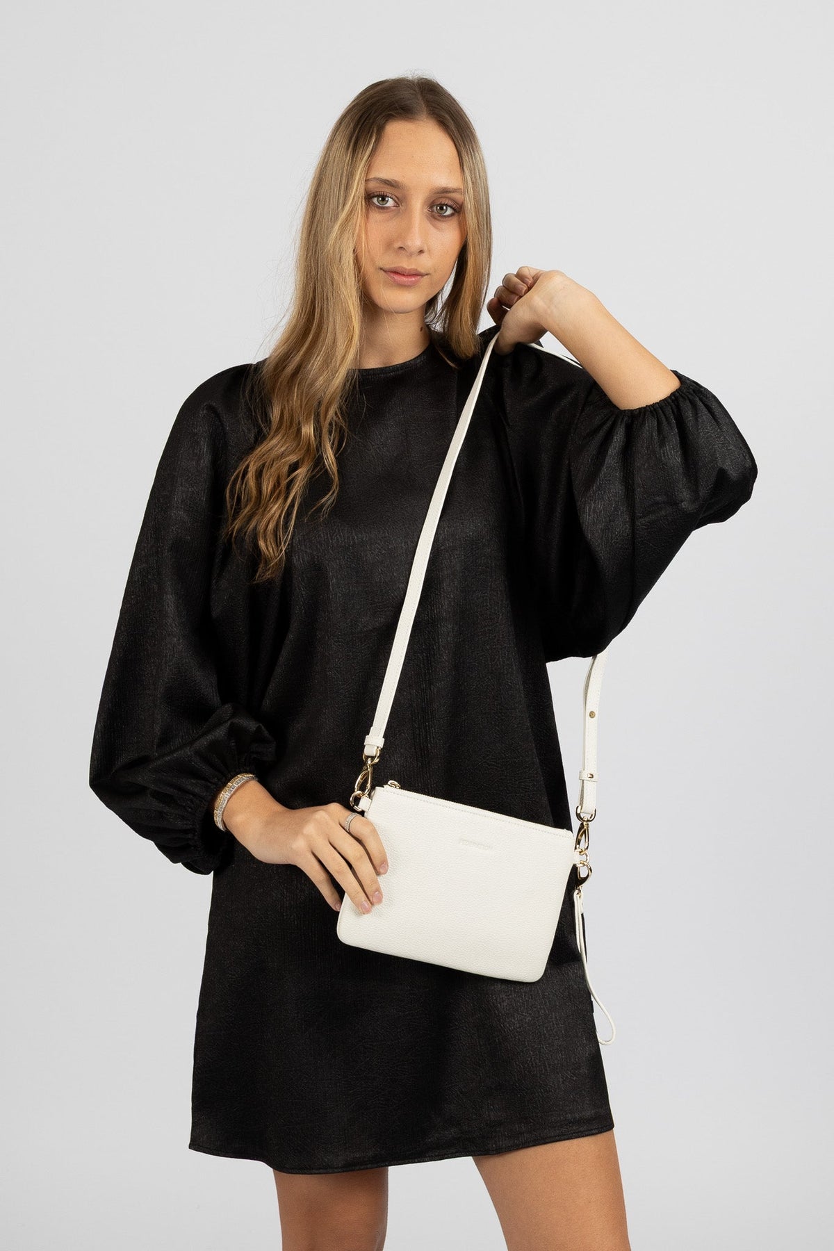 Model in a black top wearing the white Ryder leather bag on its long shoulder strap