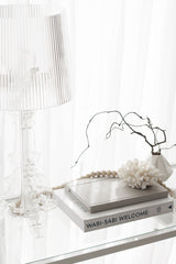 A WABI-SABI WELCOME glass table with a Books lamp and a Books book, perfect for adding minimalist home decor aesthetics.