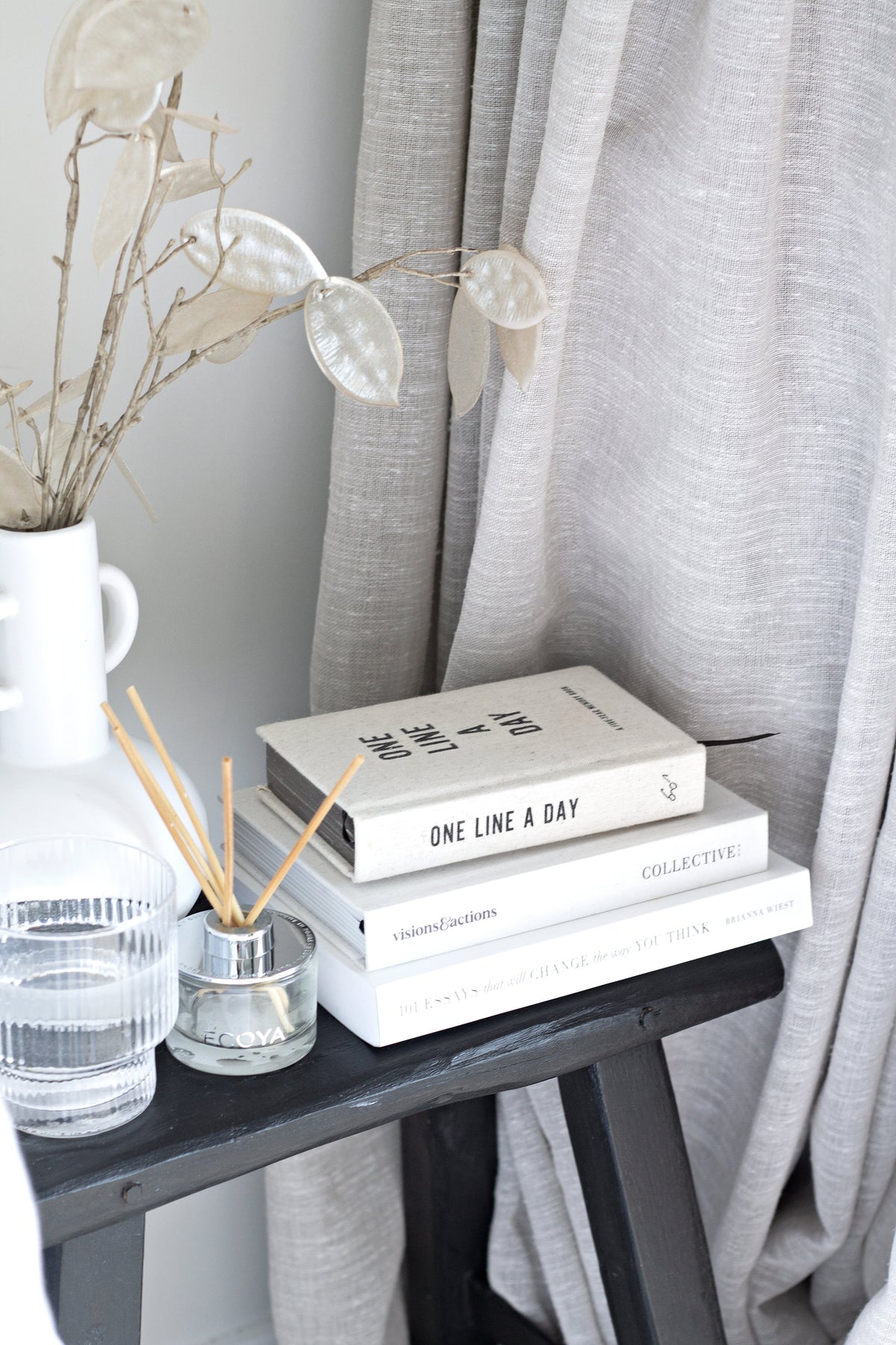 Canvas One Line a Day journal on a dark side table with books and a vase of white stems