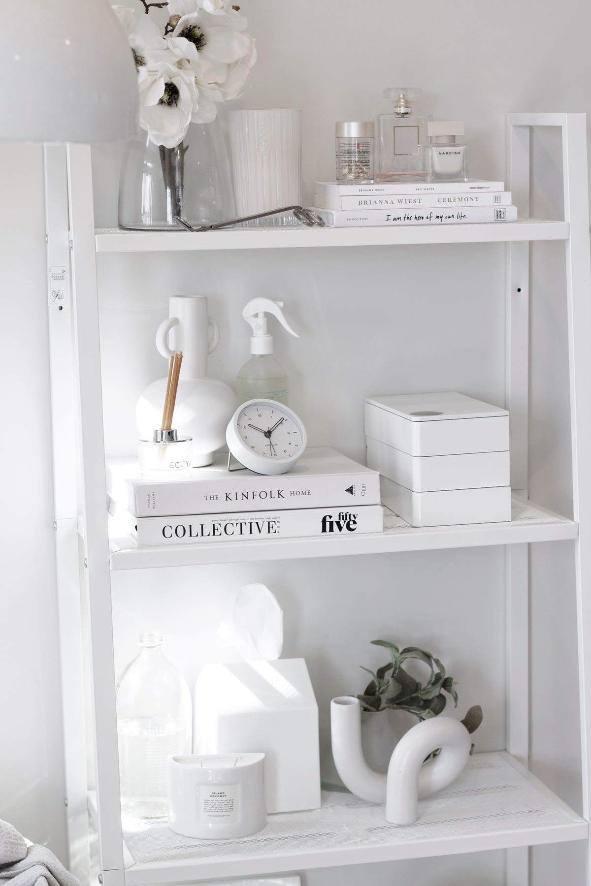White shelves styled with Collective Issue 55, white flowers, glass bottles and a knot sculpture