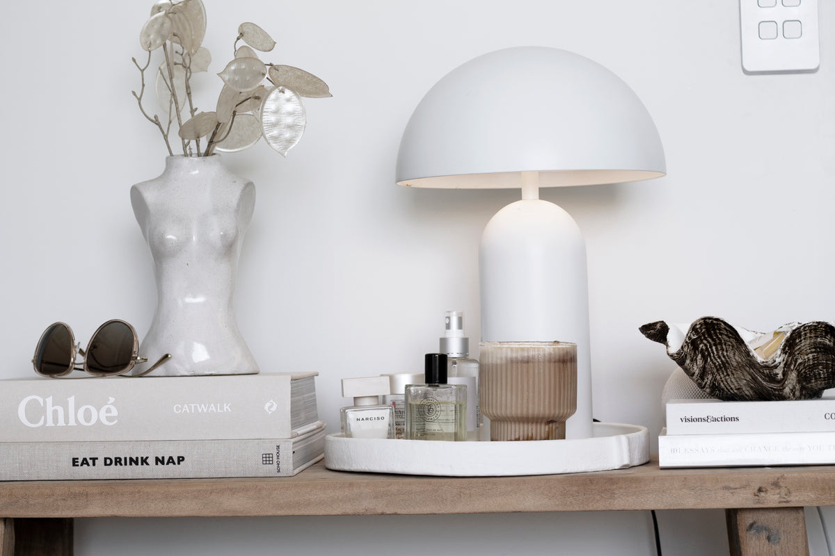 Female Silhouette Vase with dried stems on a timber shelf beside a white mushroom lamp