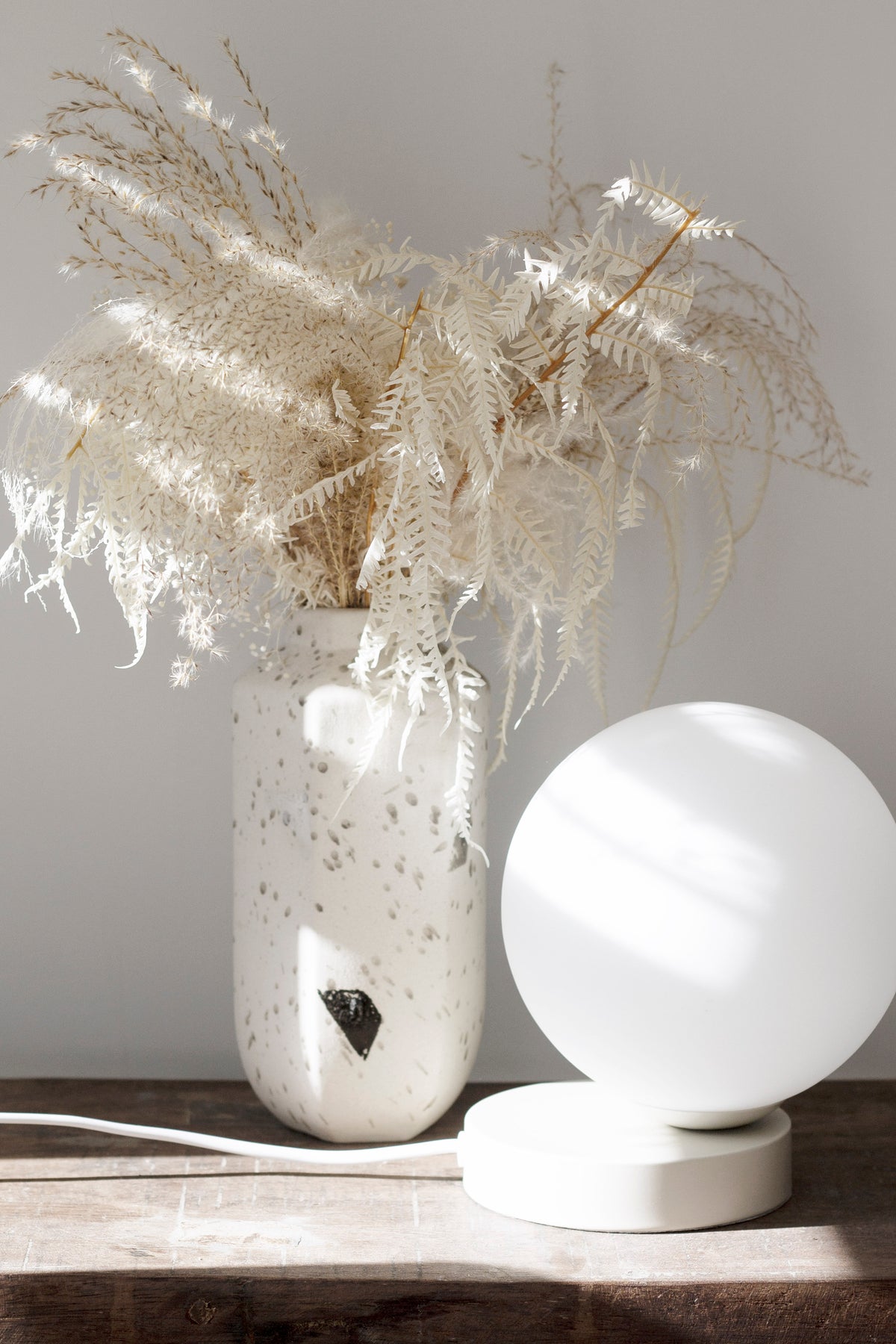 Yuri Table Lamp on a timber console beside a speckled vase of dried grasses