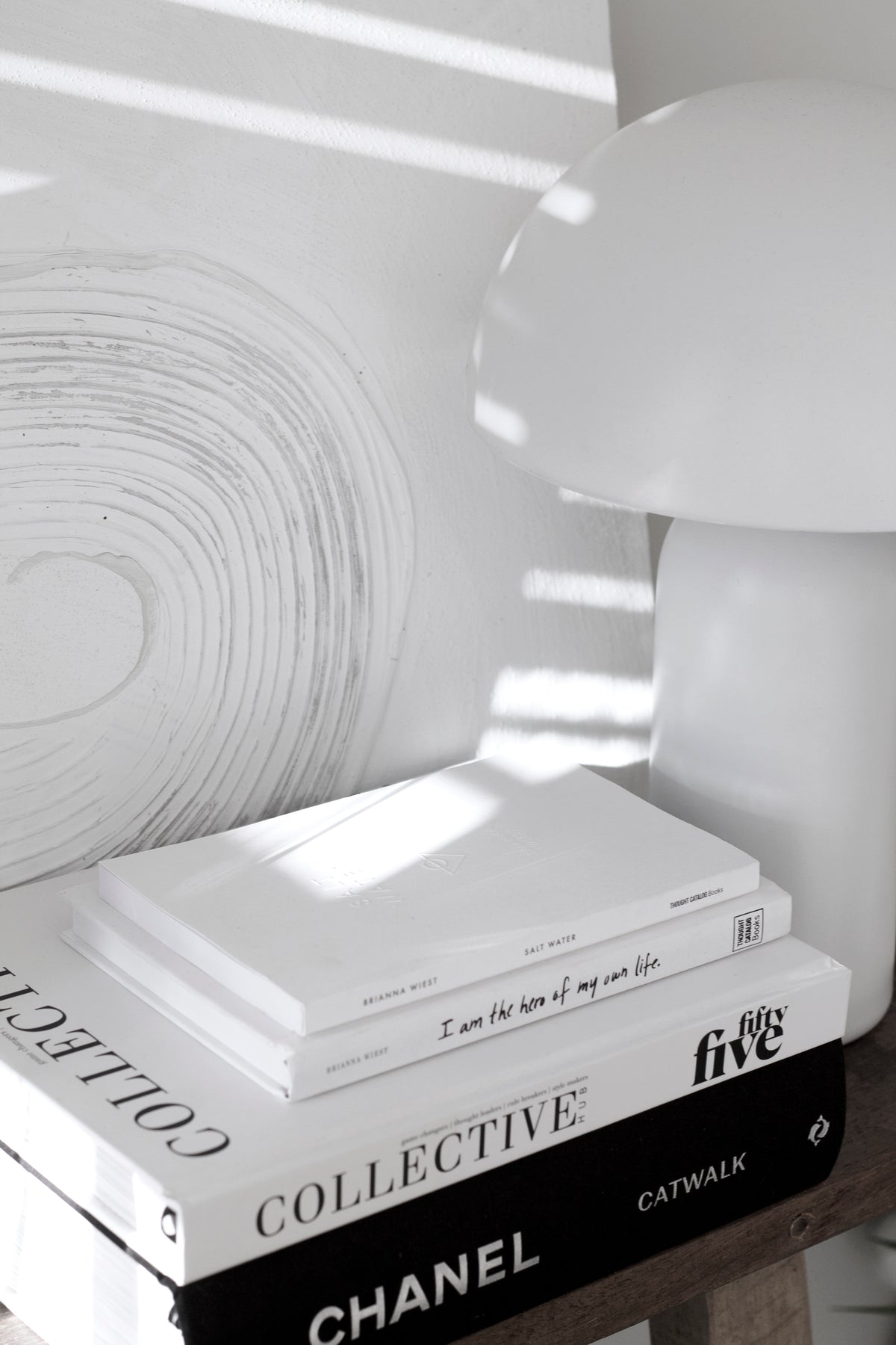 Collective Issue 55 in a stack of coffee table books beside a mushroom lamp in sunlight