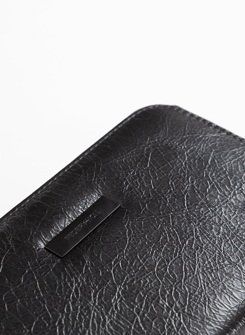 Close view of the Minky wallet's crinkled black leather and logo tab