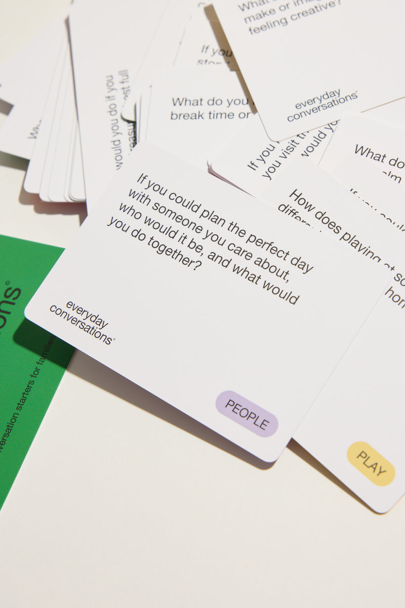 Everyday Conversations cards scattered face up, one asking about planning a perfect day with someone you care about