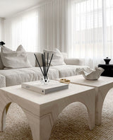 A white living room with a white coffee table adorned with Blend Aroma Sticks - Various Fragrances by The Aromatherapy Co.
