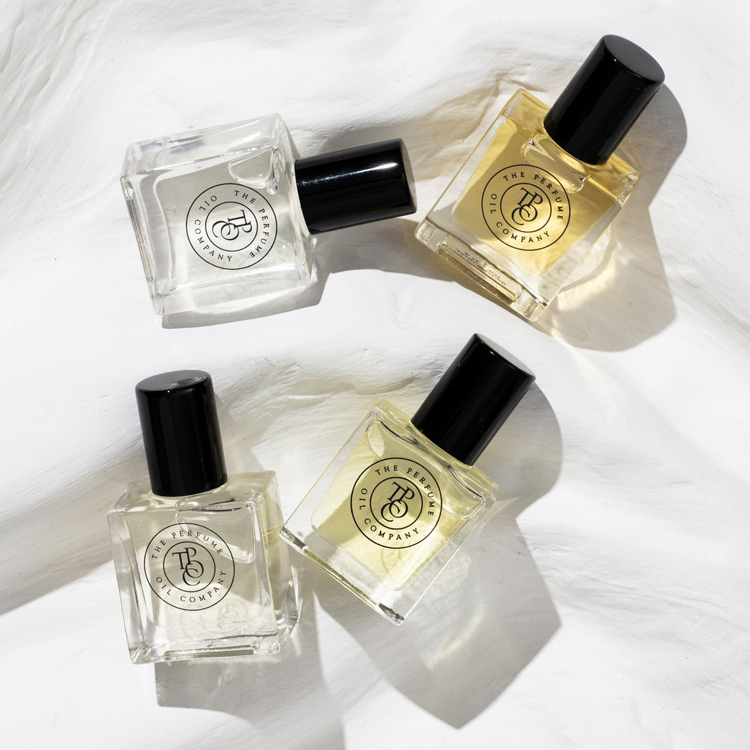Four roll-on perfume oil bottles arranged on white fabric
