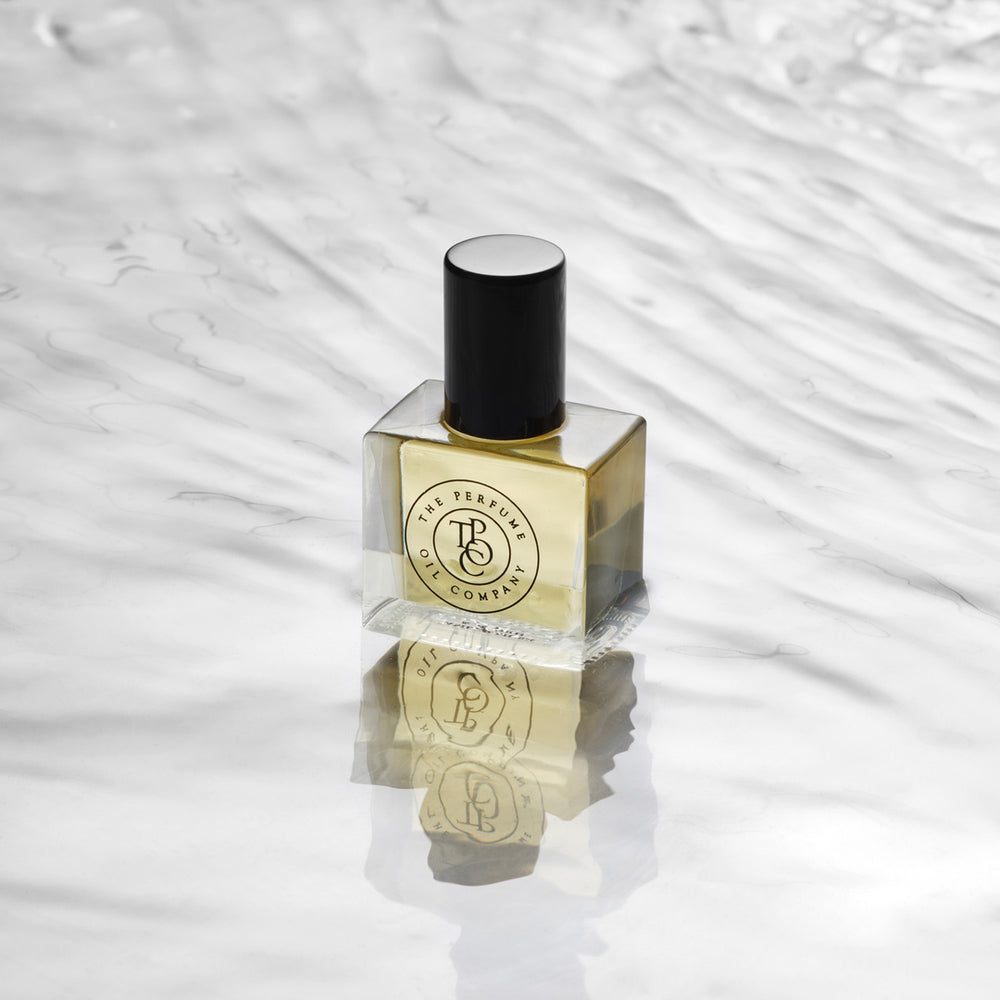 Amber perfume oil bottle with a black cap standing on a rippled water surface