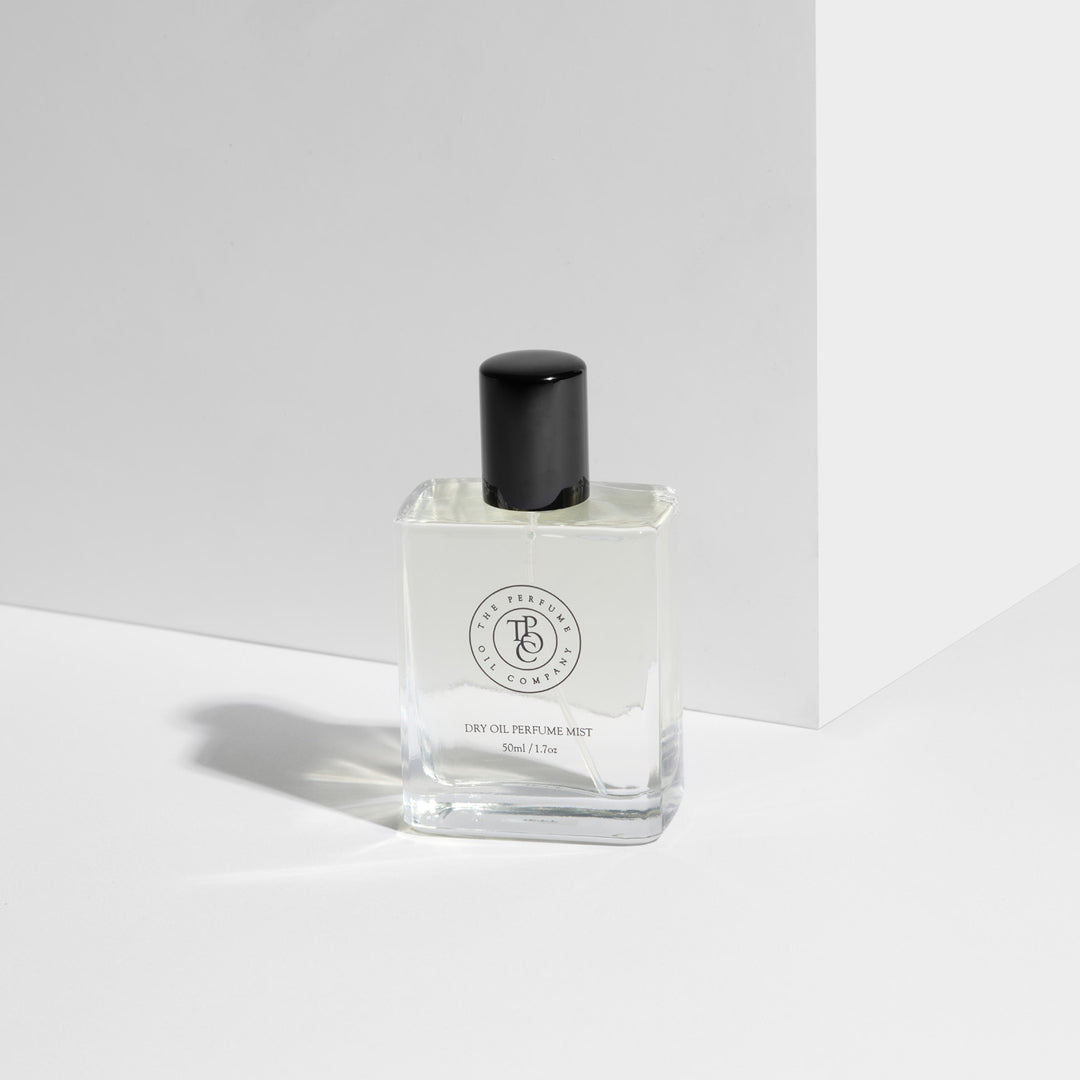 A square glass bottle of JETT dry oil perfume mist with a minimalist black cap, styled against a white geometric backdrop, capturing a modern and luxurious aesthetic.

