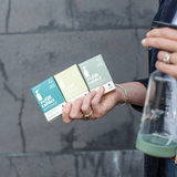 Person holding a bottle of water and Good Change refill cleaning tablets