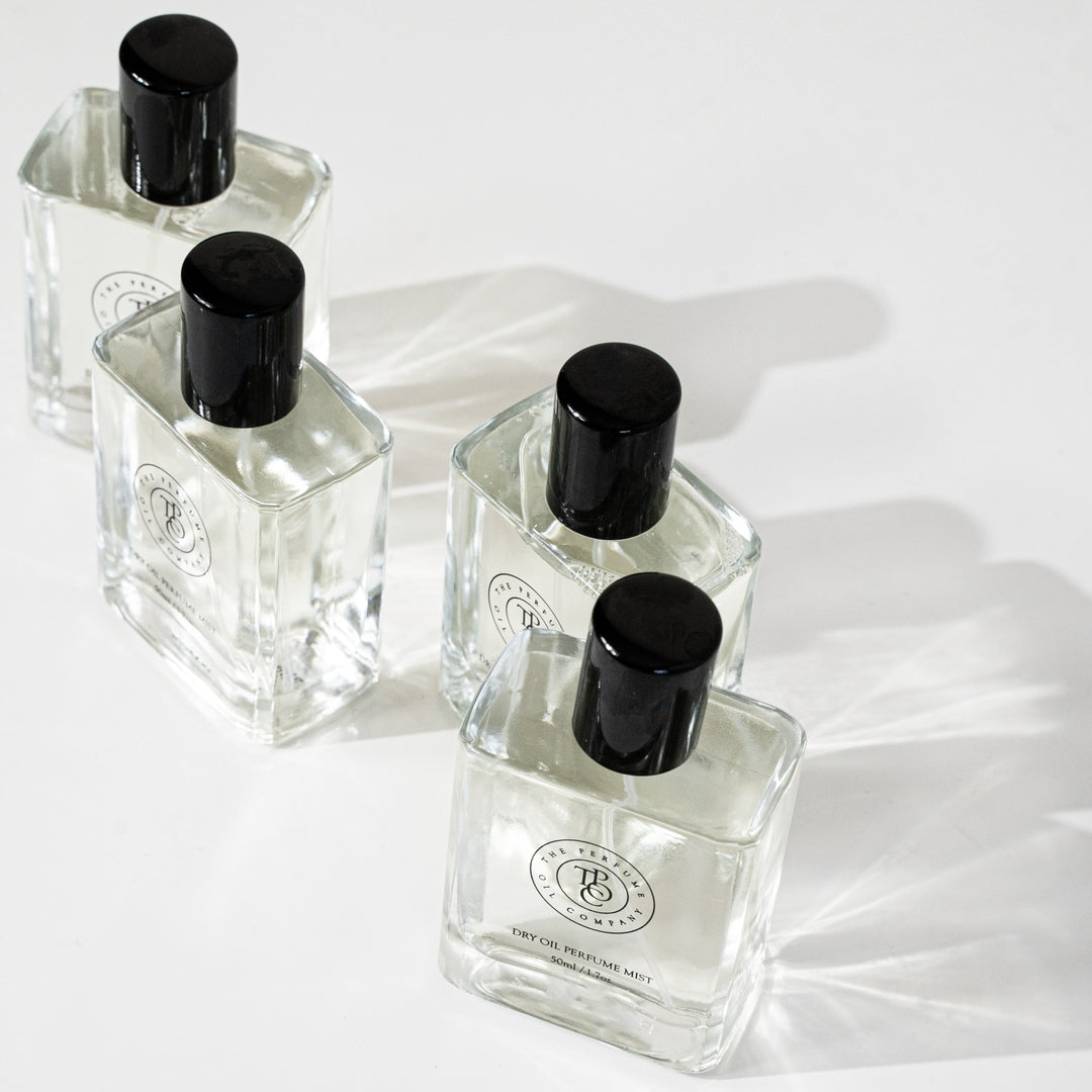Three roll-on perfume oil bottles lying on a pale grey surface