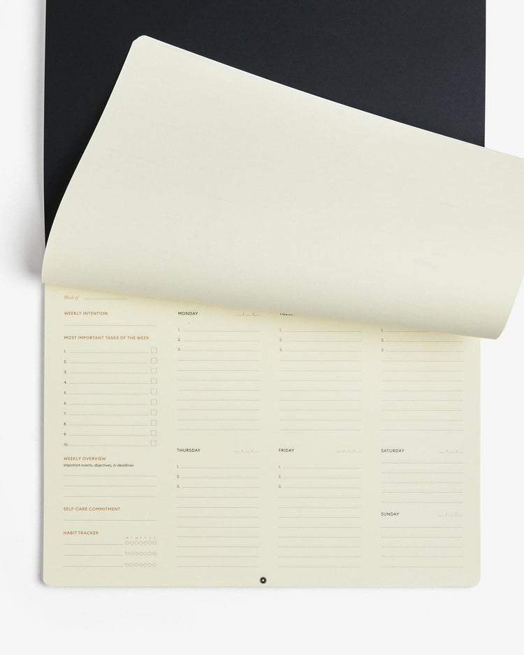 Intelligent Change weekly desk pad with a page lifted to show the undated weekly layout