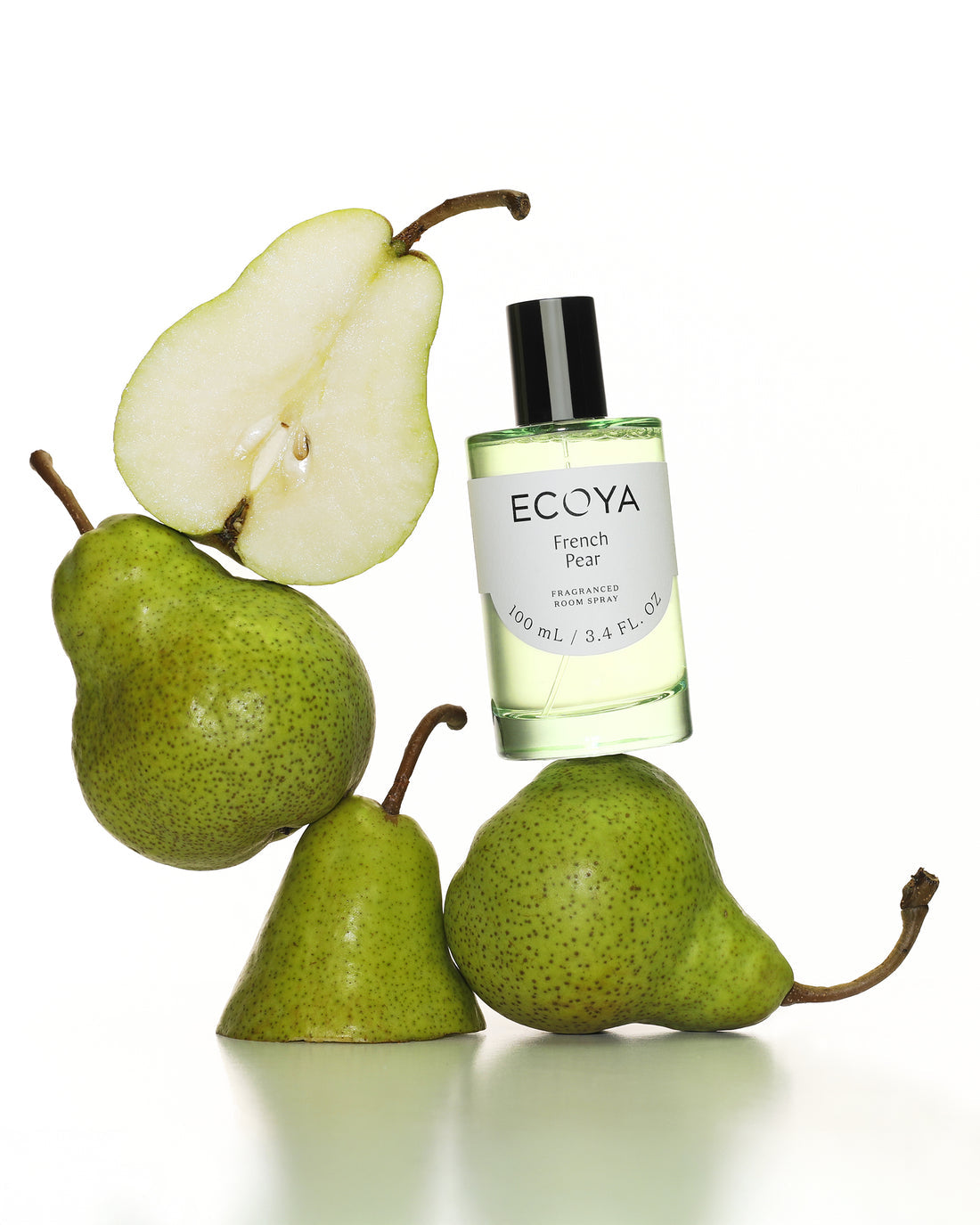 Ecoya French Pear room spray in green glass balanced among fresh green pears