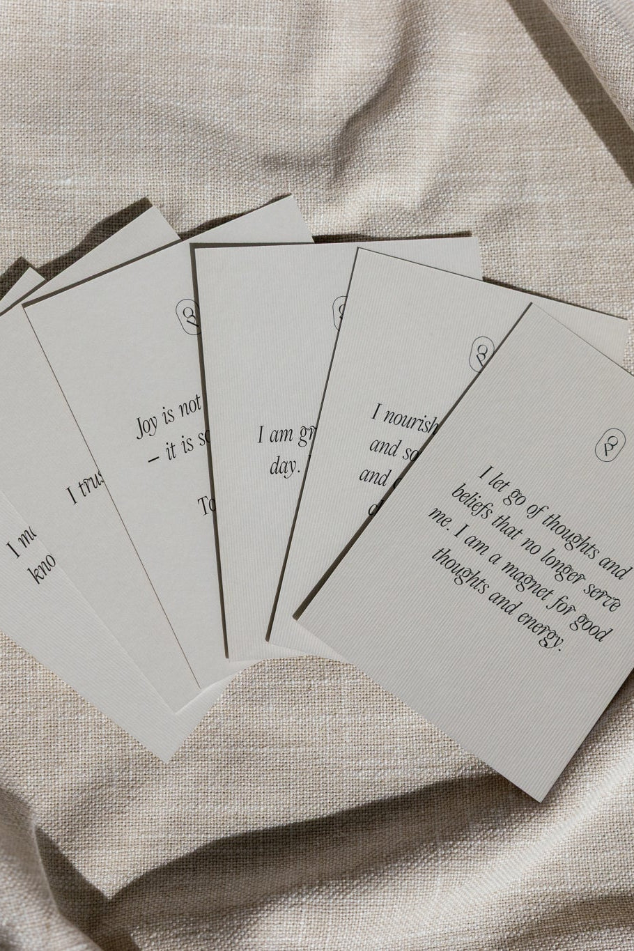 Fan of affirmation cards spread across a pale cloth