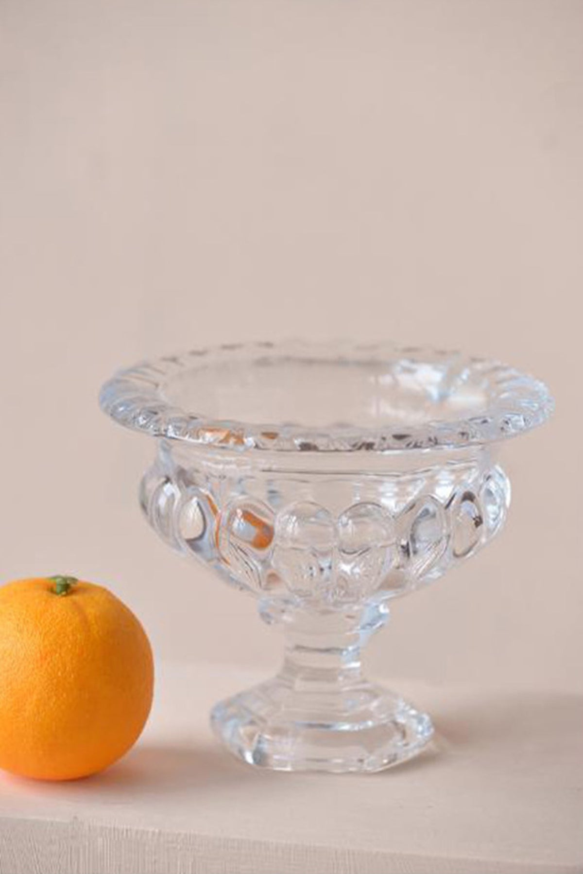Louisa footed glass pedestal bowl small size shown with an orange for scale