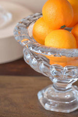 Louisa footed glass pedestal bowl styled with oranges on a wood table