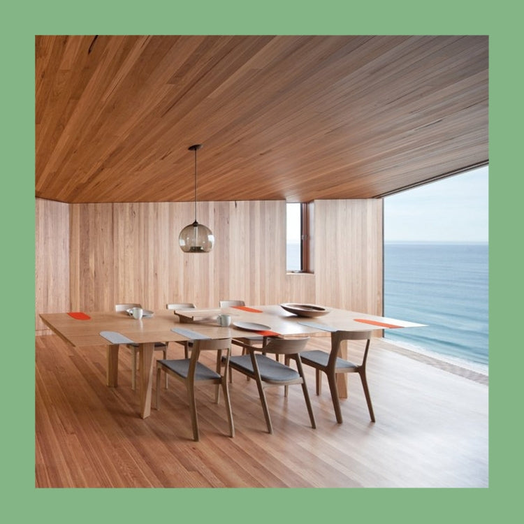 This Building Likes Me spread showing a timber lined dining room with a glass pendant and sea view