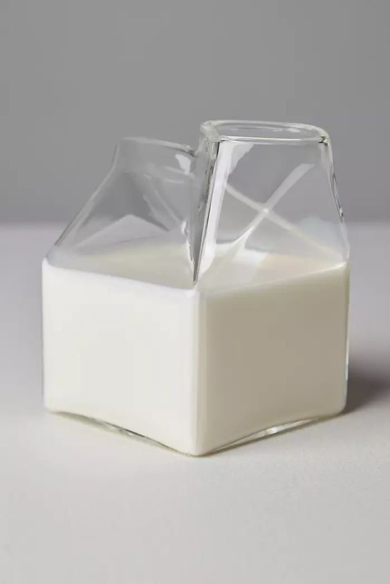 Clear glass milk carton creamer used as a small bud vase with a single stem