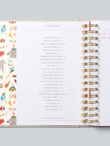 Open baby journal book with a colourful page on the left and a spiral-bound structure on the right, on a light gray background.