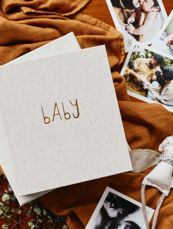 Notebook with 'BABY' on a brown blanket with family photos