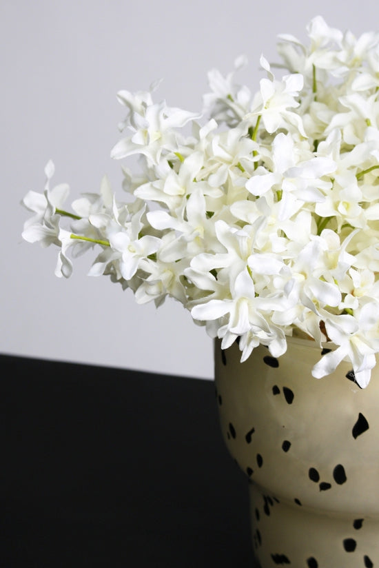 Faux orchids beside a cream book on a pale linen surface