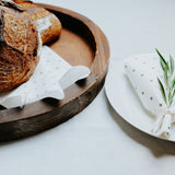 A multi-purpose Good Change reusable bamboo towel on a plate with a sprig of rosemary.