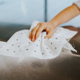 A person using a Good Change reusable bamboo towel to clean a cloth in a sink.