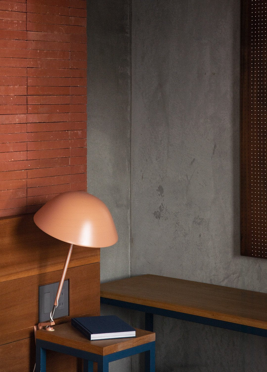 Interior featured in the book: a copper dome lamp on a timber desk against a brick wall