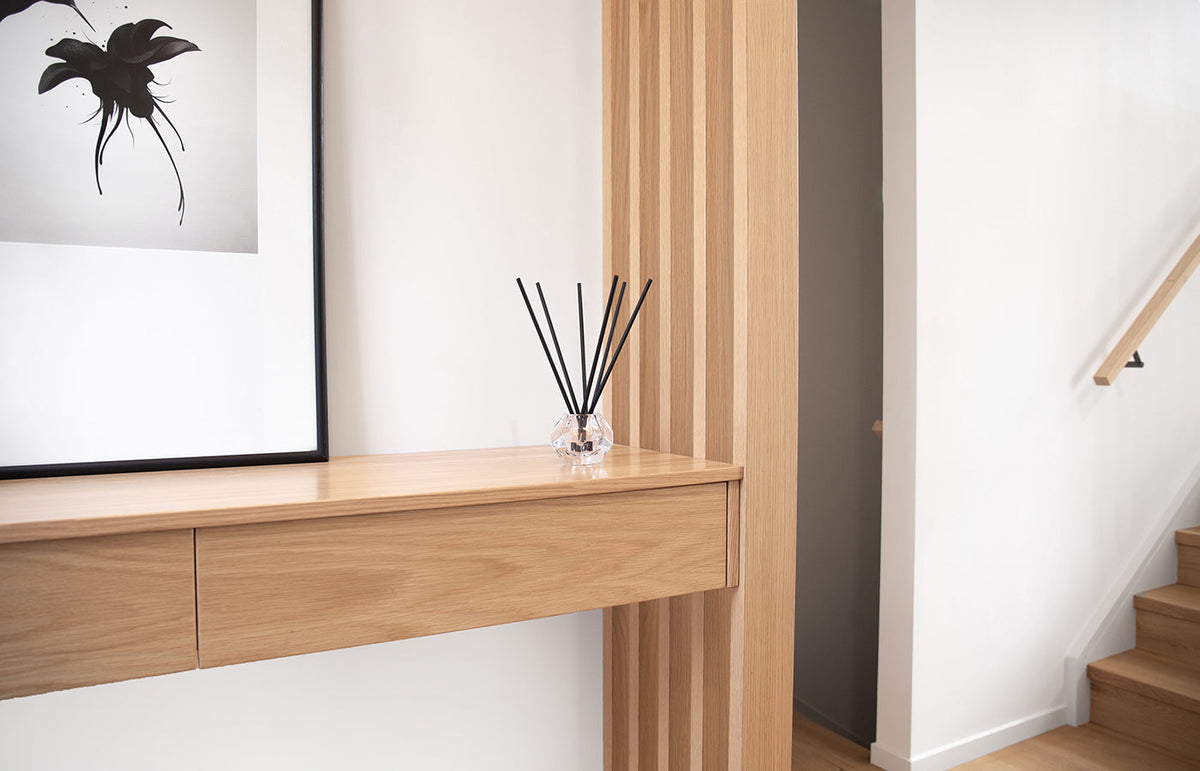 Aroma sticks on a hallway console with framed art and a stair rail behind