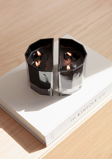 Two lit Blend candles on a white coffee table book on light oak, seen from above
