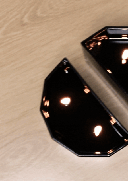 Close overhead view of a lit half-moon Blend candle reflecting flames in its black glass