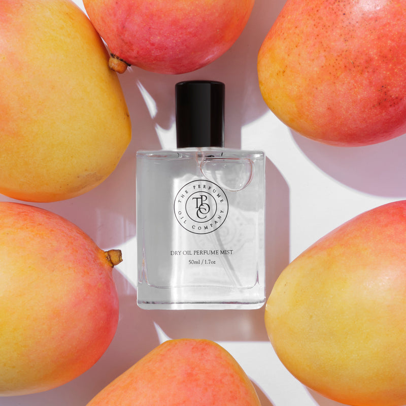 A bottle of CALYPSO perfume inspired by Mango Skin (Vilhelm Parfumerie), surrounded by mangoes.