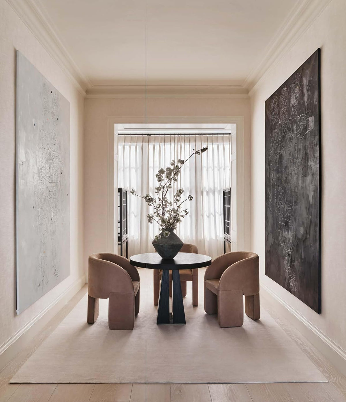 Interior from Curated Living: a dining nook with curved chairs between two large abstract canvases
