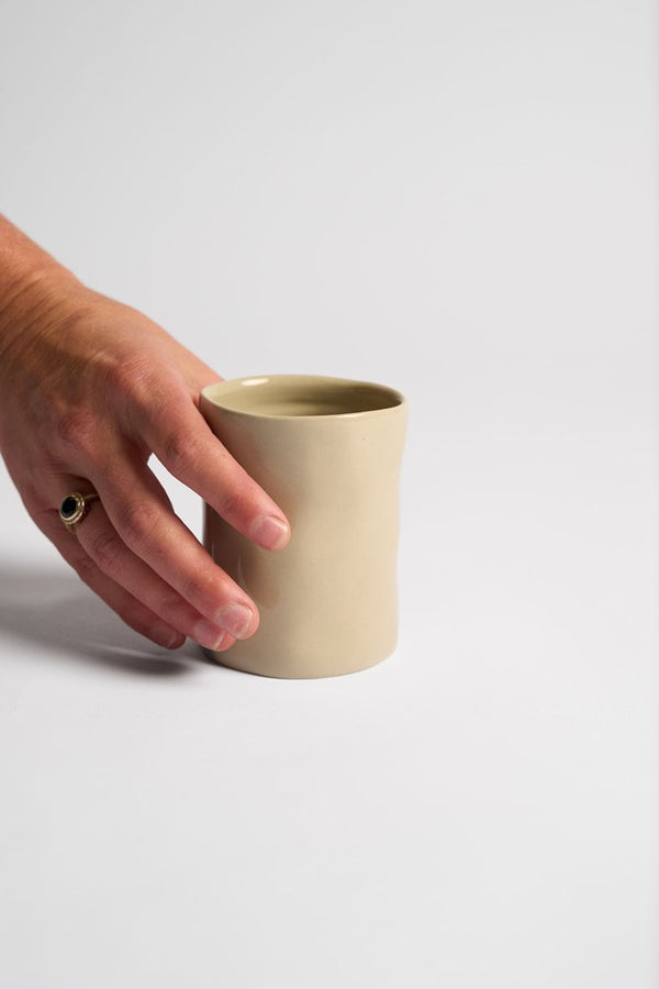 Hand placing the cashmere tumbler on a white surface