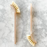 Wooden dish brush resting on a marble benchtop