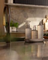 Ecoya Tahitian Lime & Grapefruit kitchen trio on a ceramic tray beside a brass kitchen tap