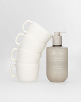 Ecoya Tahitian Lime & Grapefruit kitchen hand wash beside a stack of white ceramic mugs