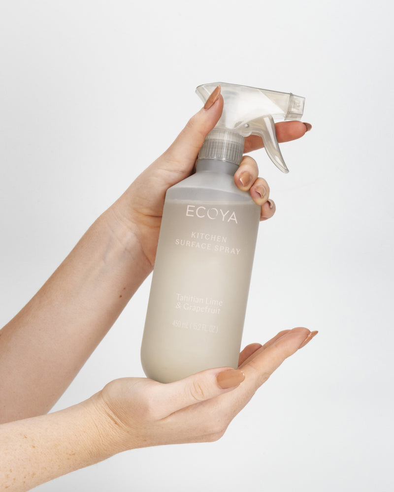 A hand holding the Ecoya Tahitian Lime & Grapefruit kitchen surface spray with its trigger top