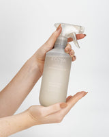 A hand holding the Ecoya Tahitian Lime & Grapefruit kitchen surface spray with its trigger top
