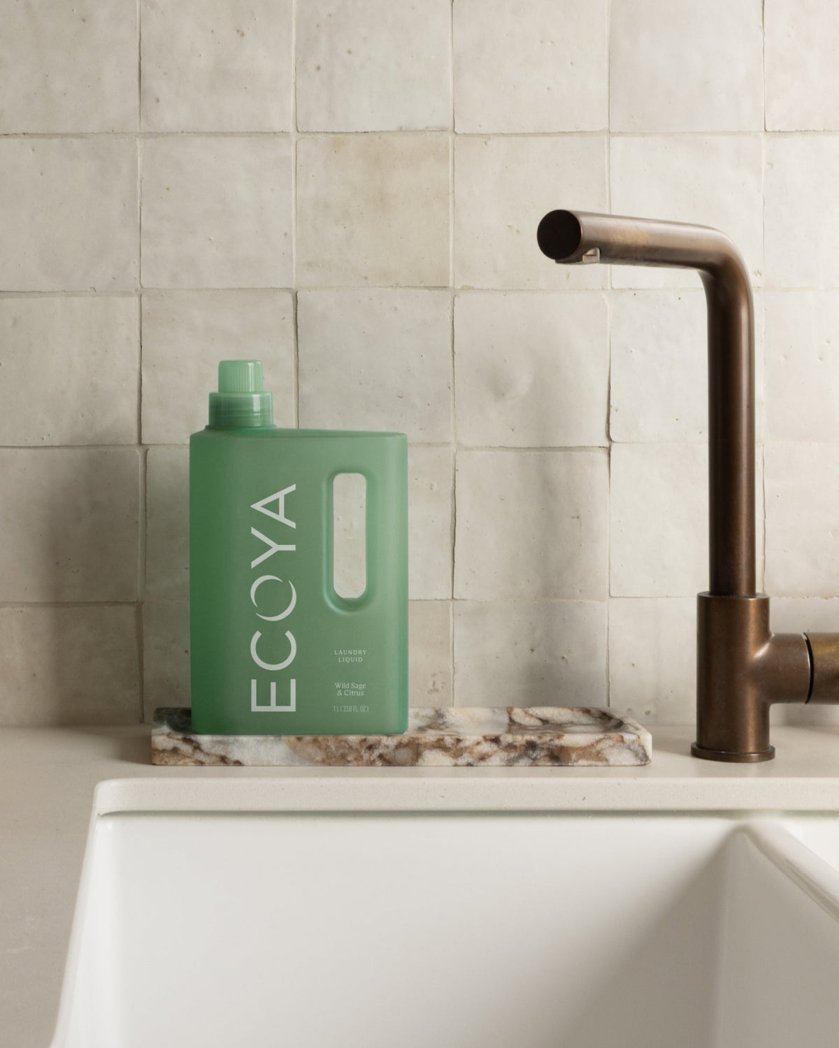 Ecoya Wild Sage and Citrus laundry liquid styled in a laundry with folded linen